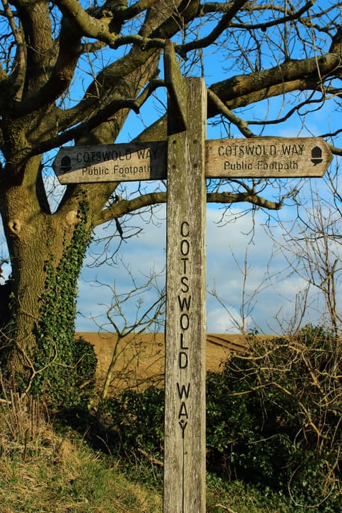 A Cotswold Way trail marker beside a country path