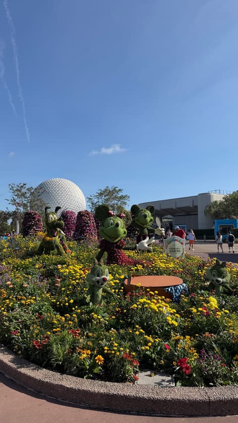 Character topiaries and colorful flower beds in front of Spaceship Earth at the Epcot Flower & Garden Festival