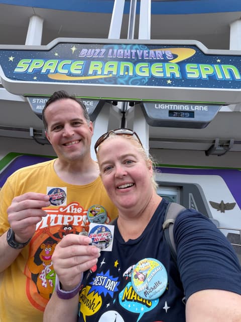 Michelle and her husband holding up their scores at Buzz Lightyear’s Space Ranger Spin in Magic Kingdom